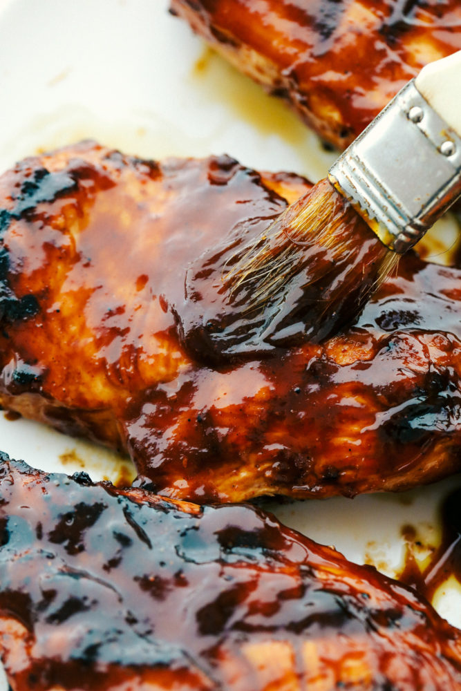 Brushing barbecue sauce on grilled chicken.