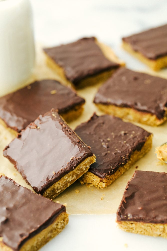 Peanut butter bars on parchments paper in squares, ready to eat. 