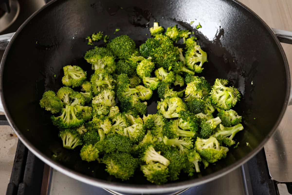 Overhead shot of broccoli sautéing in a skillet. 