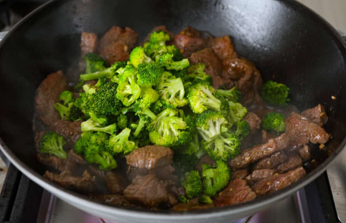 Overhead shot of broccoli and flank steak sautéing in a skillet. 