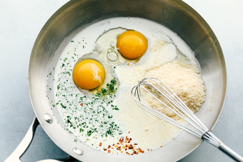 eggs and seasonings in a skillet ready to make the sauce for bacon carbonara.