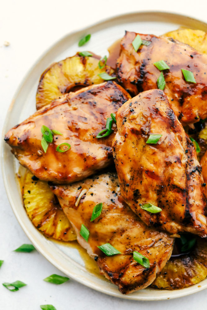 Grilled Hawaiian chicken on a white plate with grilled pineapple underneath. 