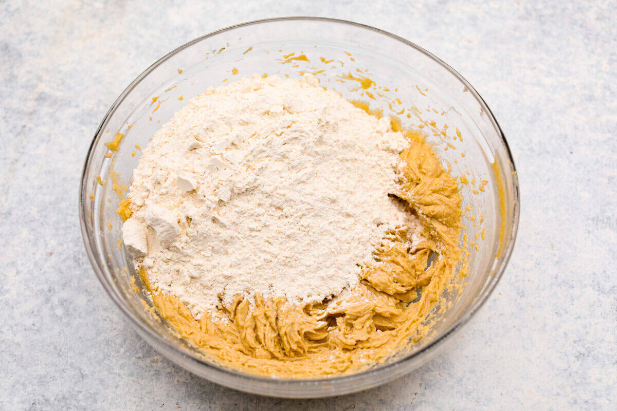 Overhead shot of flour dry ingredients on top of the wet ingredients in a bowl. 