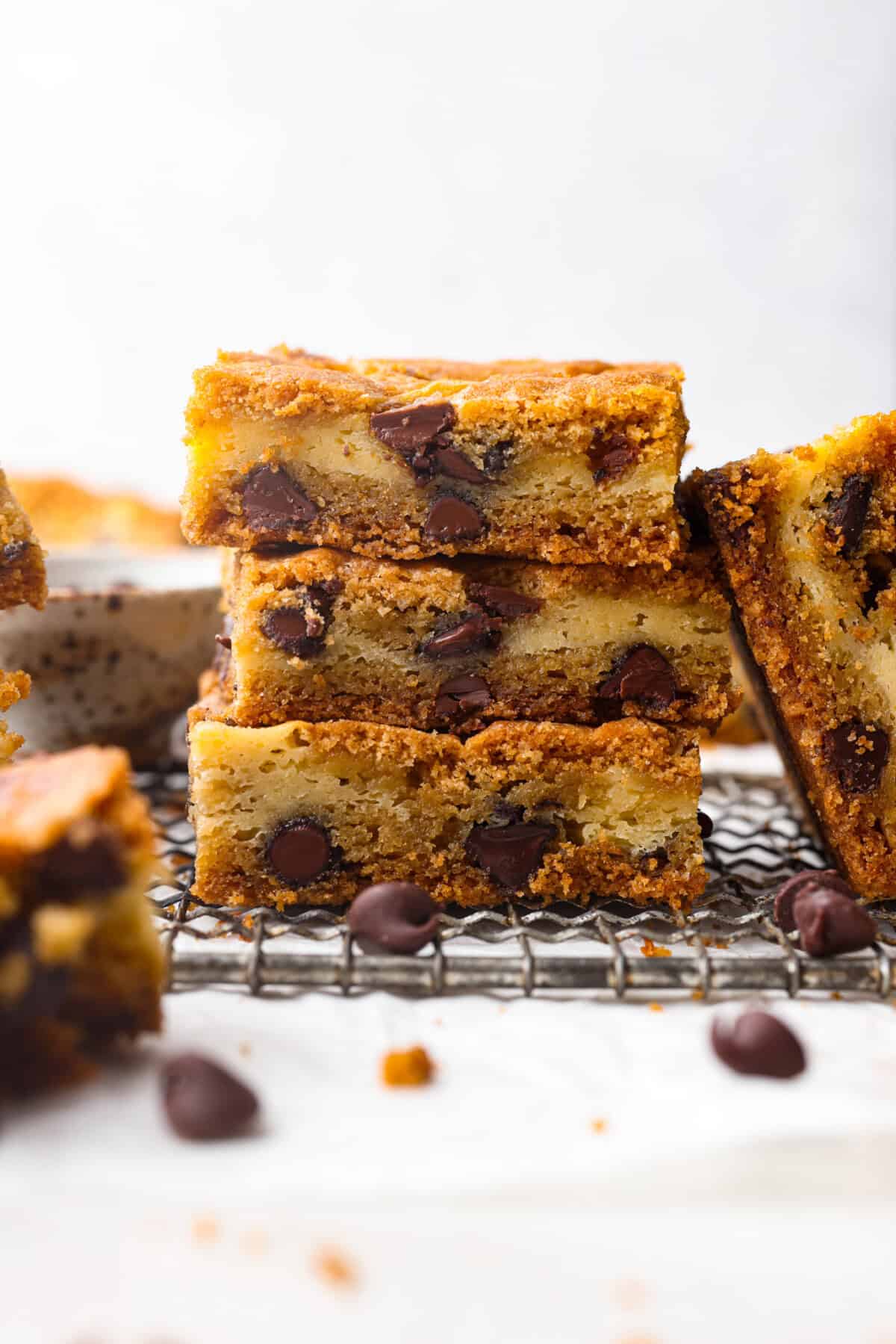 Side shot of stacked chocolate chip cheesecake brownies. 