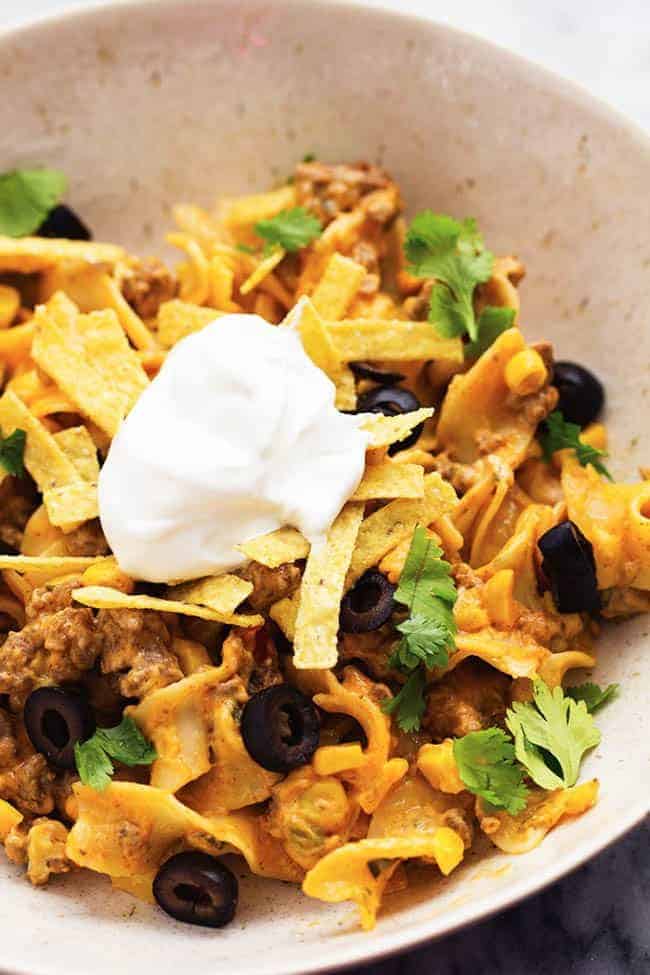 taco stroganoff on a tortilla with sour cream and tortilla chip garnish.