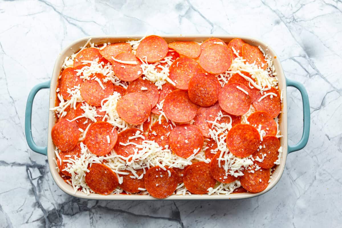 Overhead shot of baking dish with uncooked pizza casserole ready to go in the oven. 