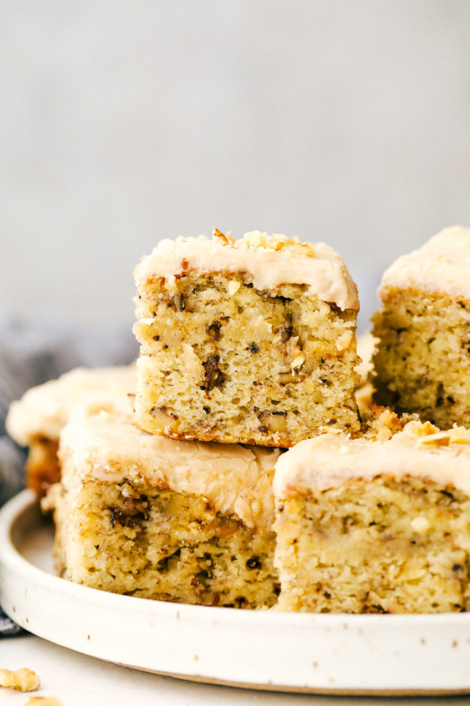 Banana bread bars on a white plate stacked on top of each other. 