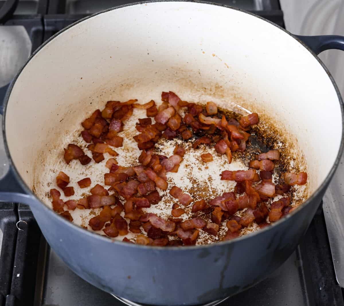 Angle shot of bacon cooking in a large pot.