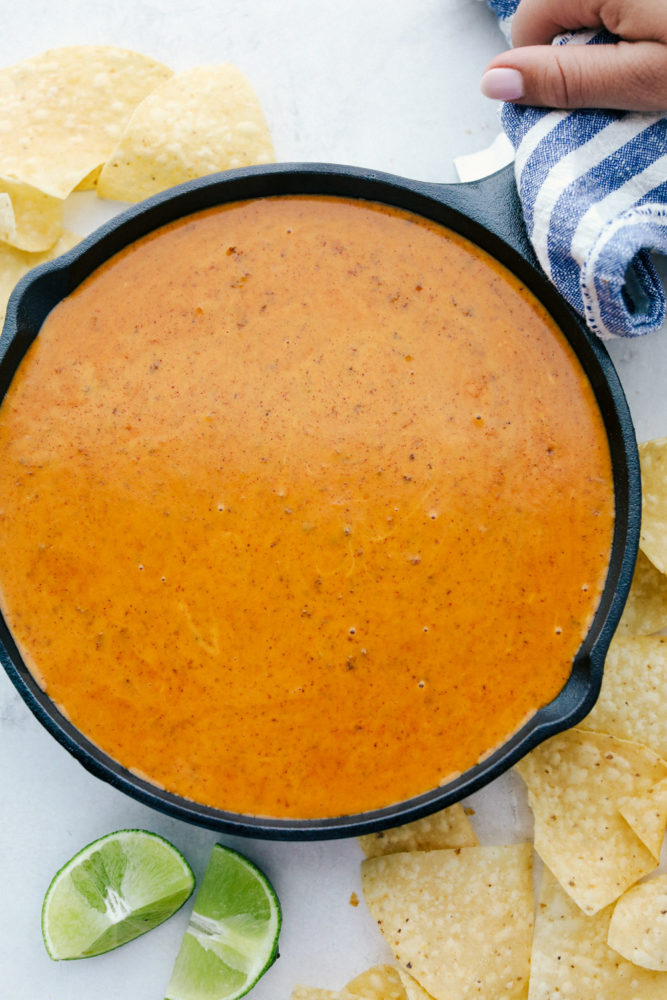 Copycat queso in a black skillet with chips all around. 