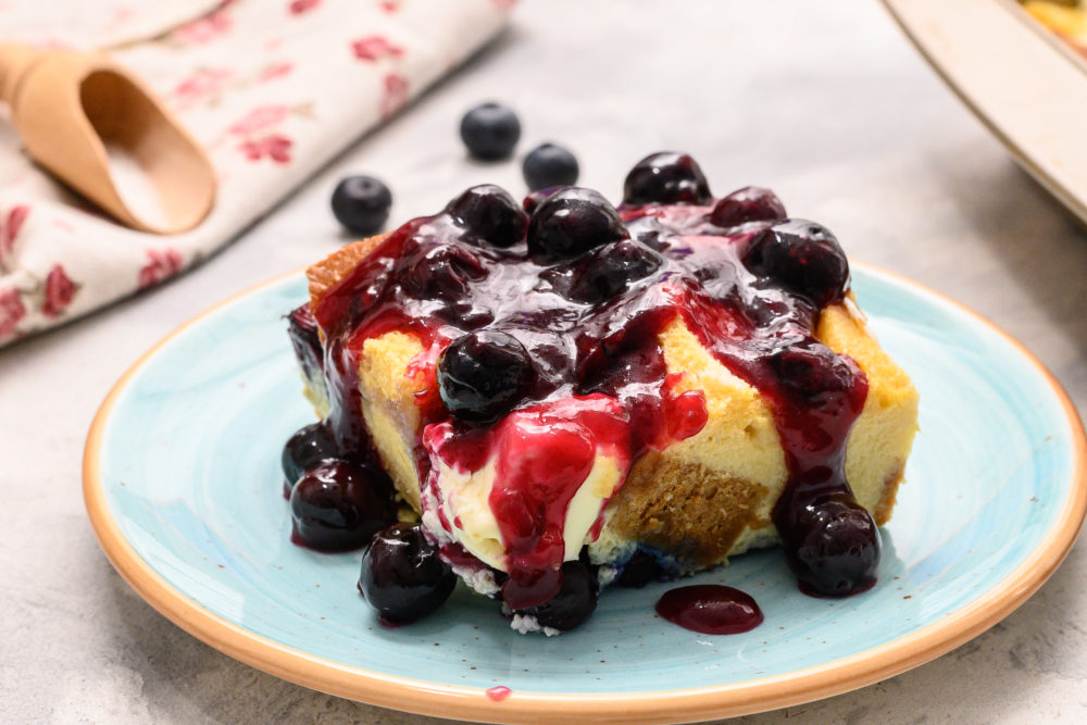 Overnight blueberry French toast on a plate topped with blueberries and syrup. 