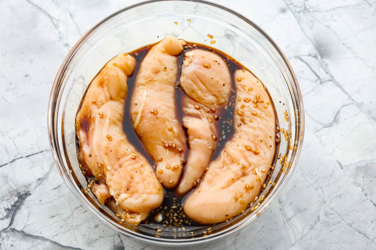 Overhead shot of chicken breasts in marinade in a bowl. 