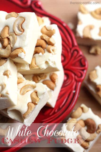 White chocolate cashew fudge stacked on top of each other on a red plate. 