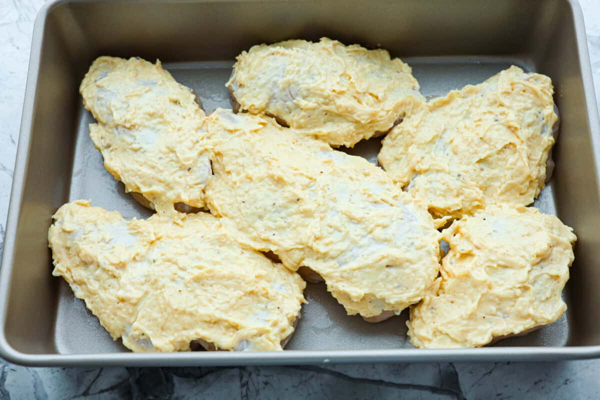 Overhead shot of chicken breasts with mayo mixture spread over the top. 