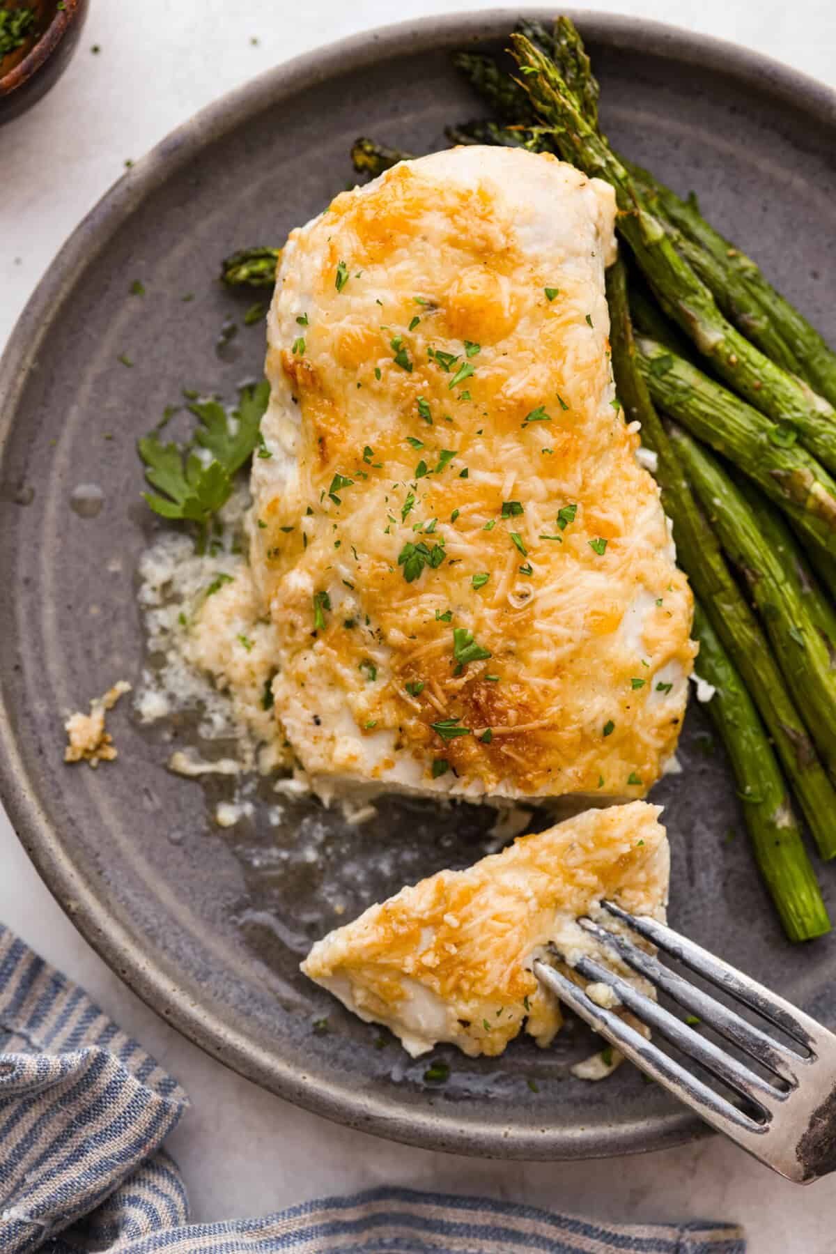 Overhead shot of plated parmesan chicken next to grilled asparagus. 