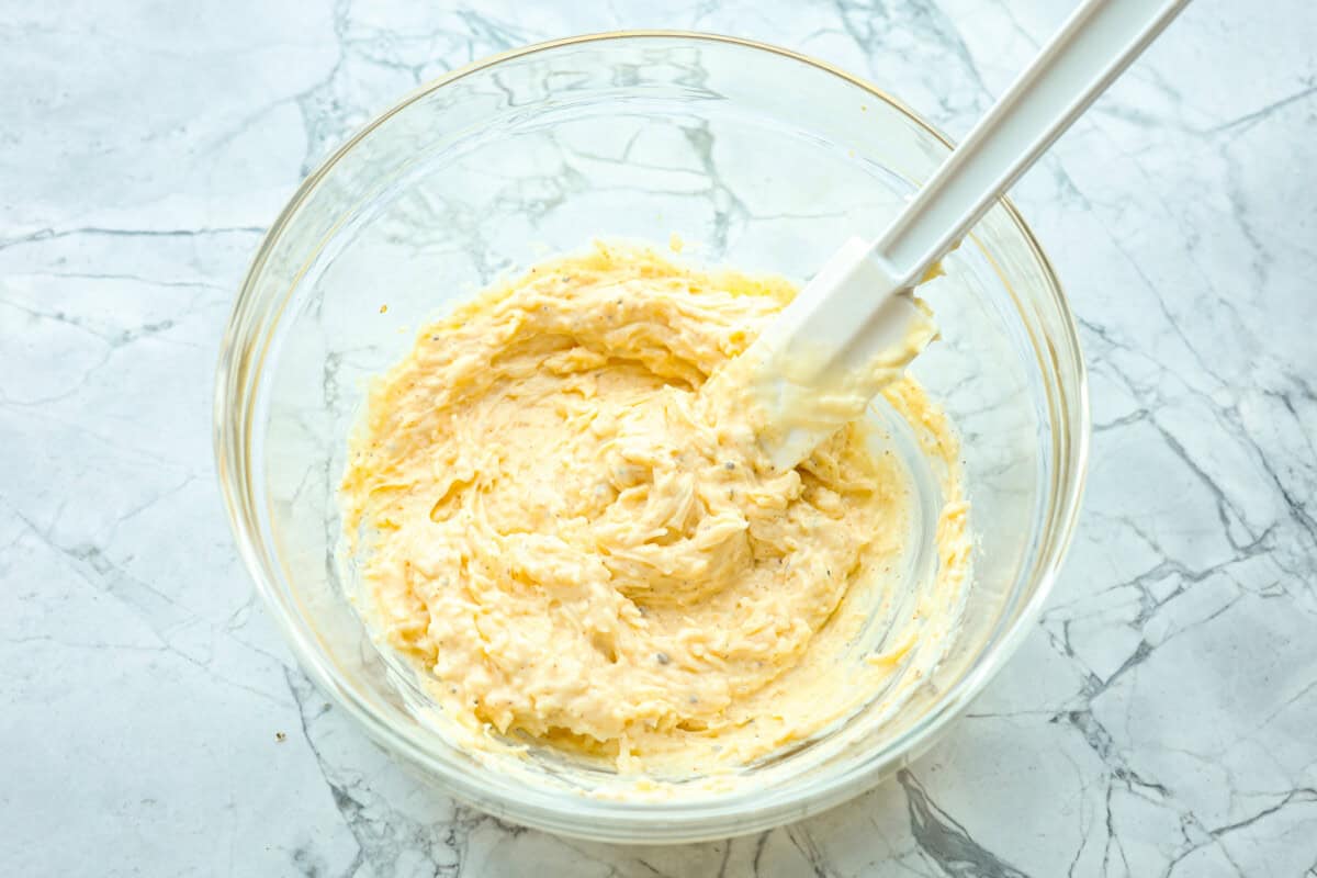 Overhead shot of mayo, cheese and seasonings mixed together in a glass bowl. 