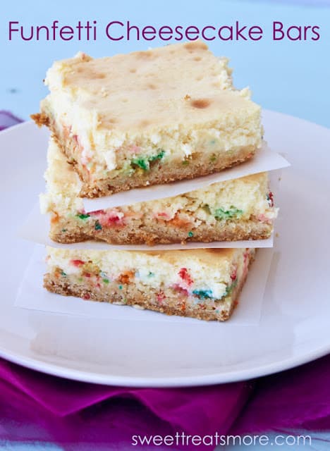 3 funfetti cheesecake bars stacked on top of each other with a white square paper between each. They are sitting on a white plate.