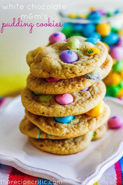 White chocolate M&Ms Pudding Cookies stacked on white plate