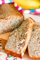 Funfetti banana bread loaf with 2 slices cut off laying beside the loaf.