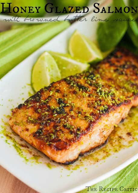 Honey glazed salmon with browned butter lime sauce on a white plate with 3 lime slices.