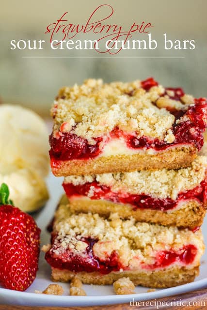 Strawberry Pie sour cream crumb bars in a stack of 3 beside a scoop of vanilla ice cream and a strawberry.