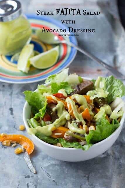 Steak fajita salad with avacado dressing in a white bowl.