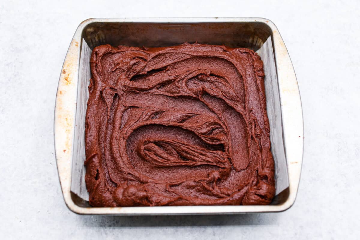 Fourth photo of the brownie batter spread into a baking pan.