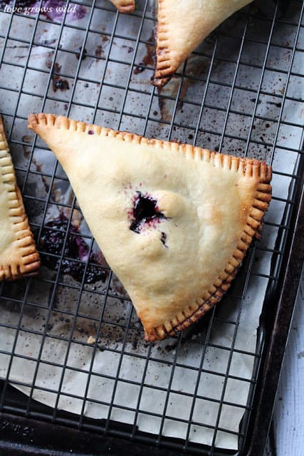 Blueberries and Cream Hand Pies on a cooling rack by LoveGrowsWild.com for The Recipe Critic