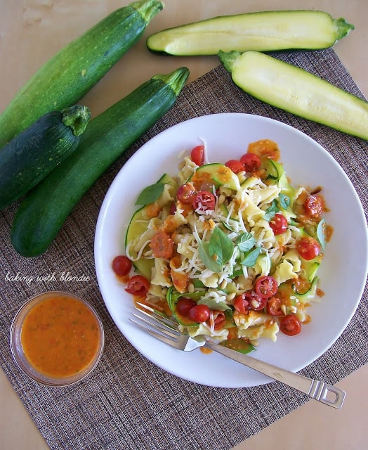 Garden Campanelle Salad with Fresh Tomato Basil Dressing on a white plate with a fork on he plate and zucchini on the side.