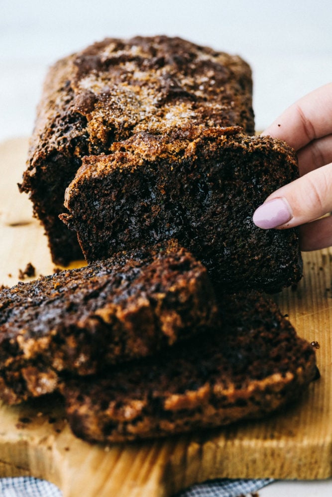 Chocolate zucchini bread sliced in three pieces on a cutting block. 