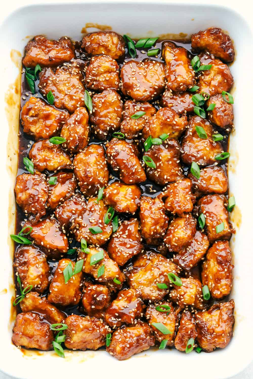 Baked honey sesame chicken in a white dish.