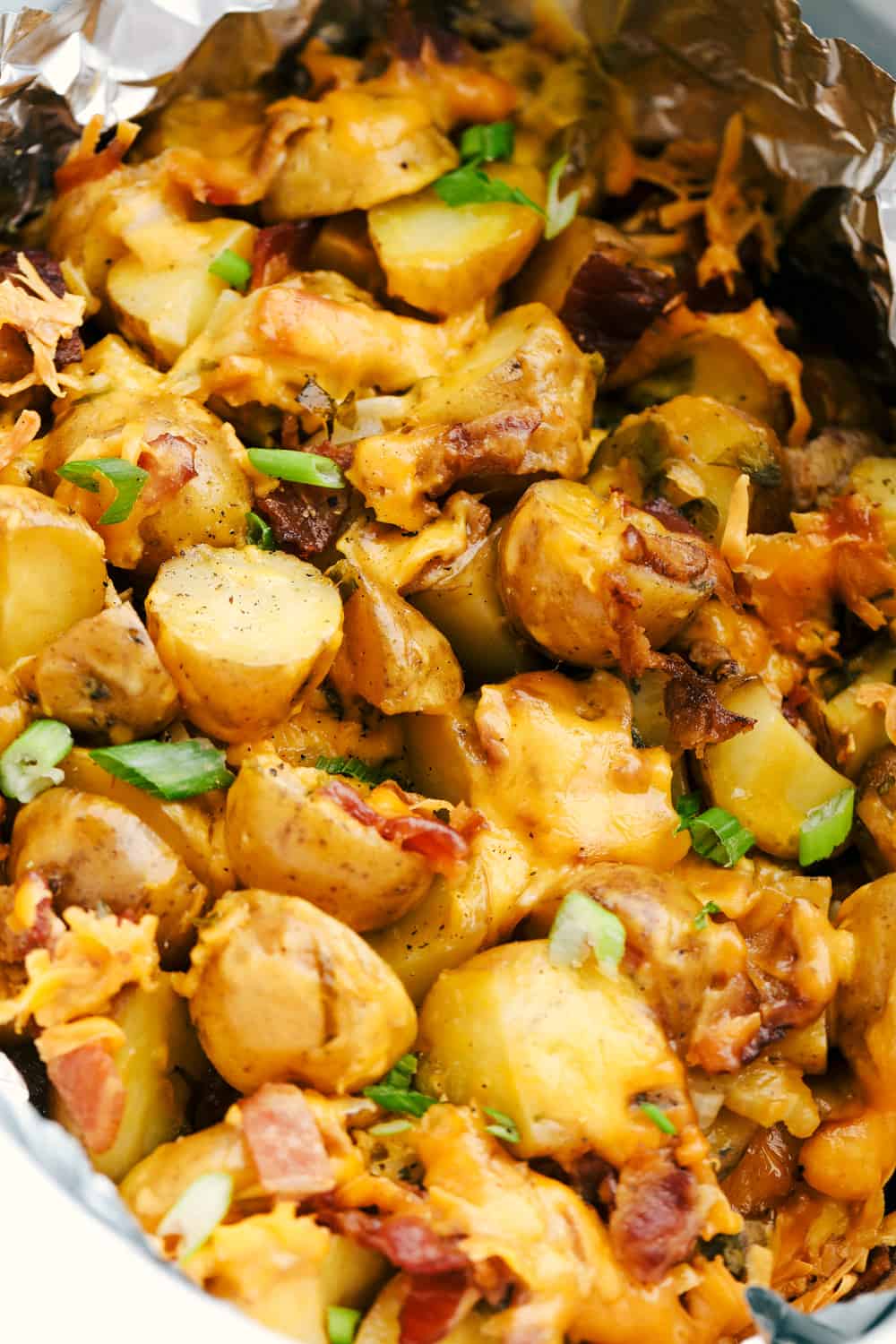 Up close photo of the cheesy ranch bacon potatoes in a slow cooker with foil. 