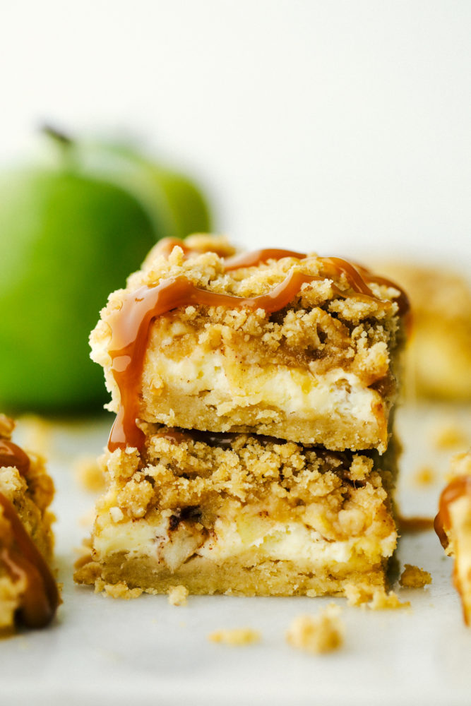 Two caramel apple cheesecake bars stacked on top of each other. 