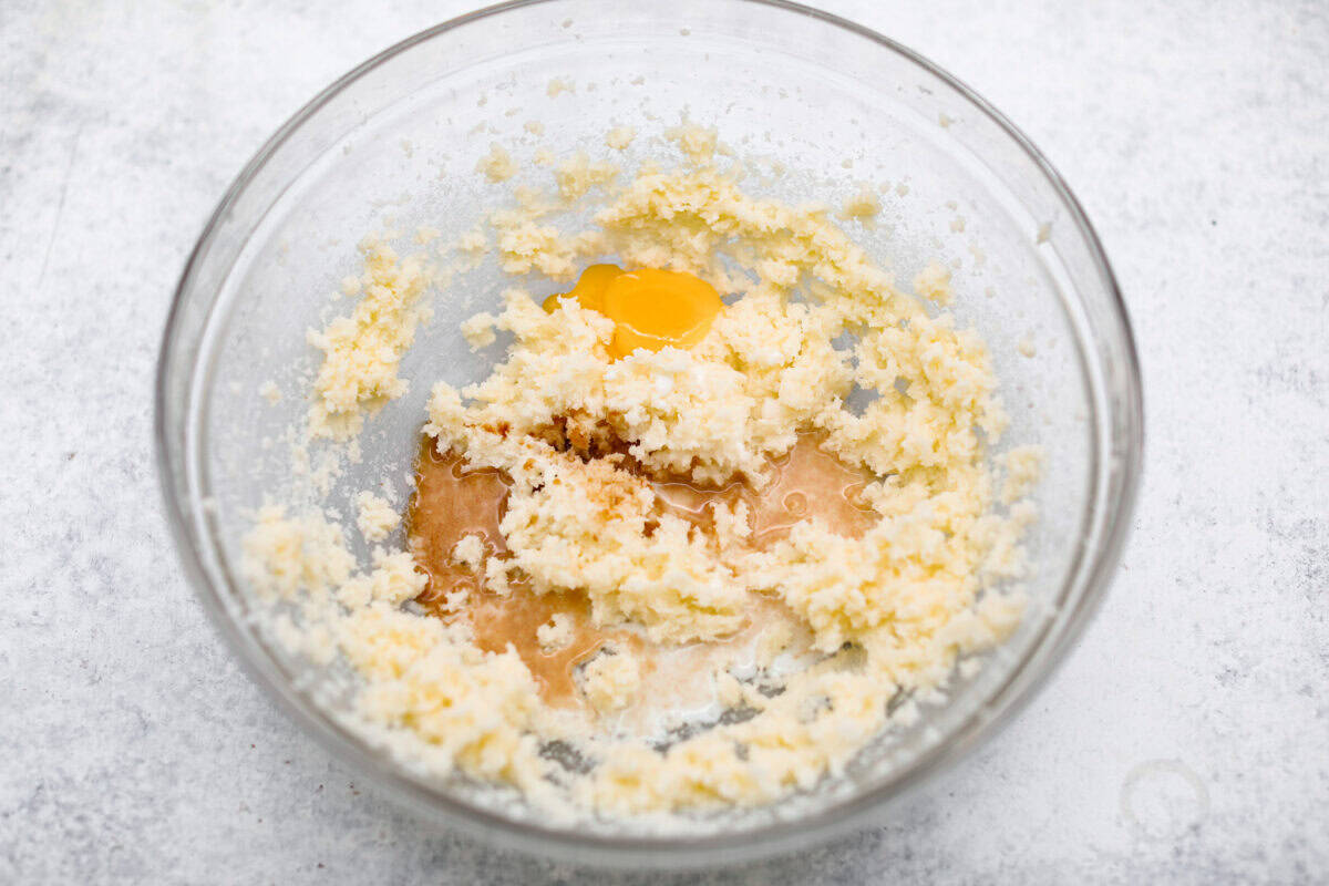 Overhead shot of creamed butter and sugar in bowl with vanilla, milk and egg yolk.