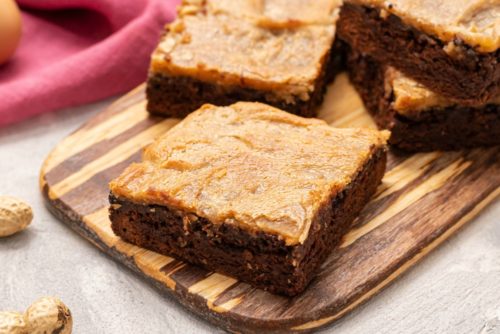 Peanut Butter Cheesecake Brownie Bars on a wooden cutting board. 