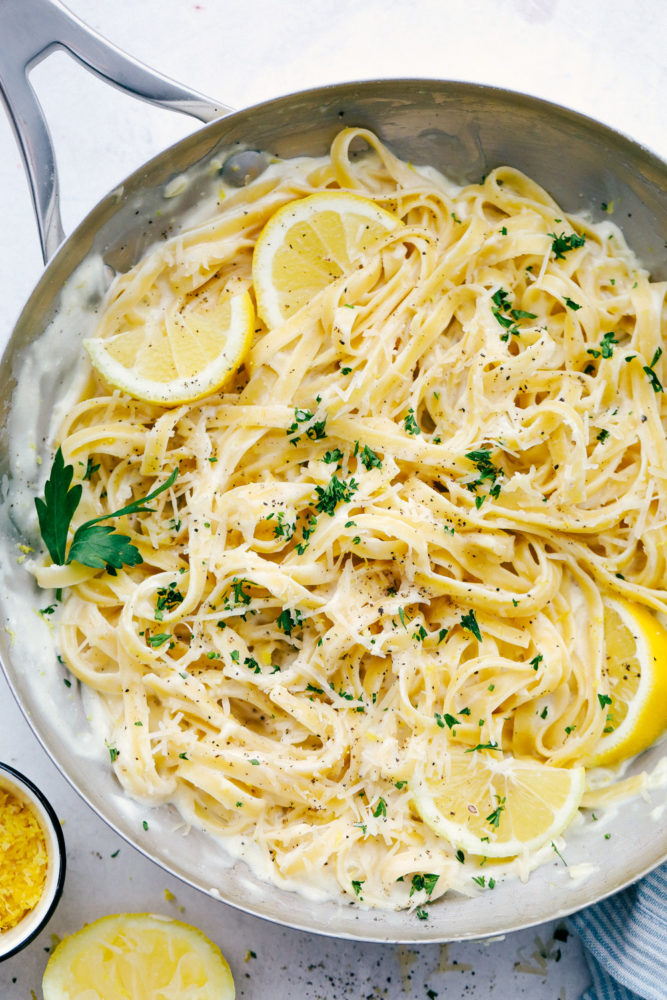 Lemon Garlic Cream Fettuccini in a frying pan with sliced lemon mixed in. 