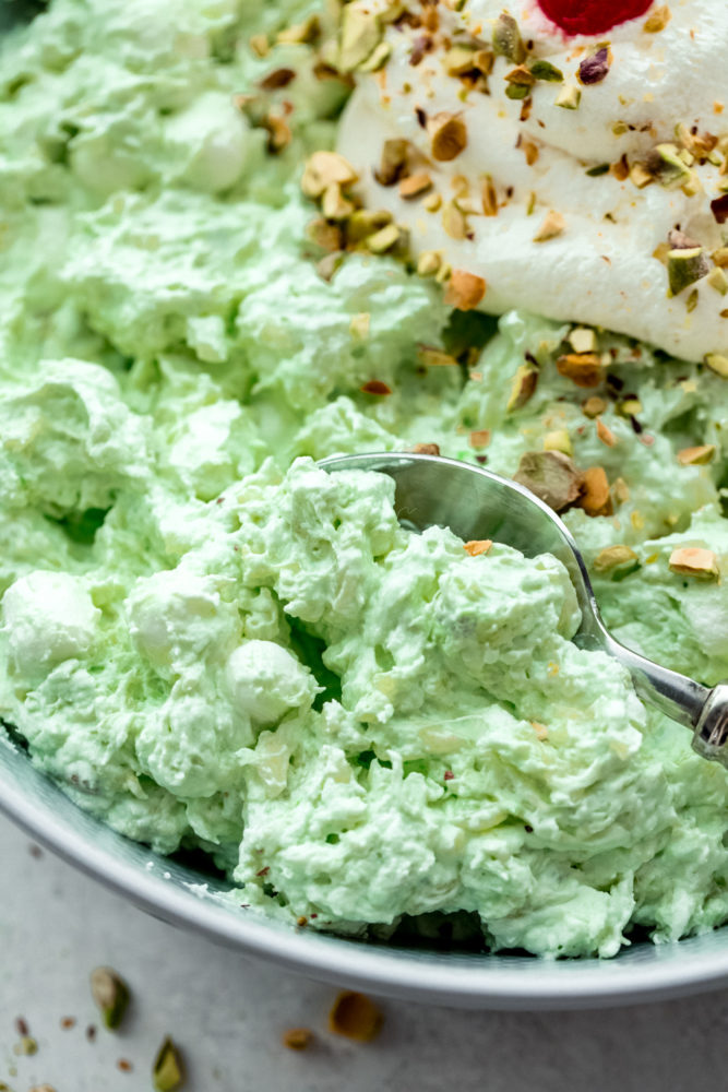 Up close photo of pistachio pudding in a bowl with a silver spoon on the side. 