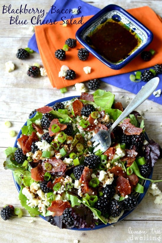 Blackberry, Bacon & Blue Cheese Salad in a blue bowl with a metal fork and dressing on the side. 