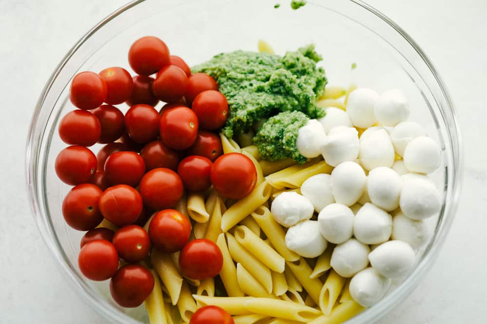 Ingredients for Caprese Pasta Salad in a white bowl. 