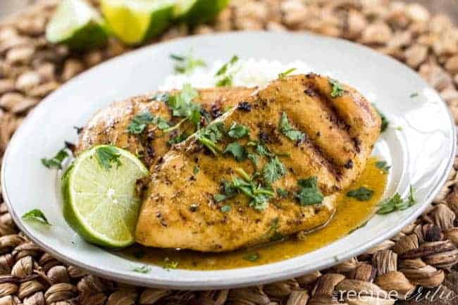 Grilled Lime Coconut Chicken on a white plate with sliced lime on the side. 