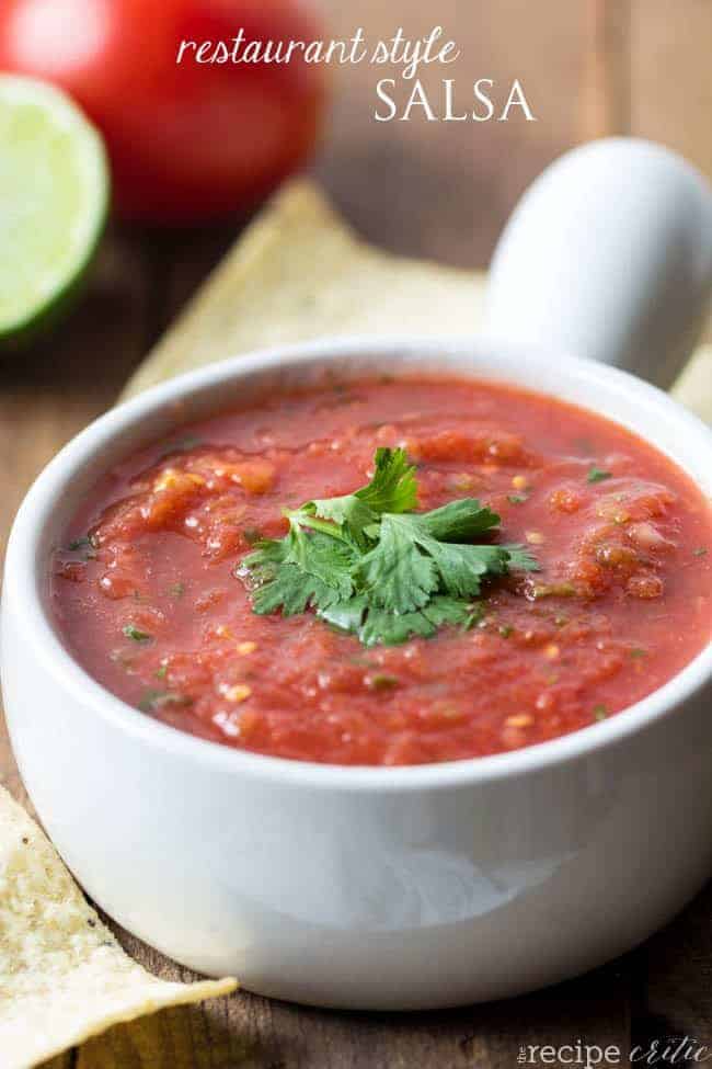 Restaurant style salsa in a white bowl with chips all around. 