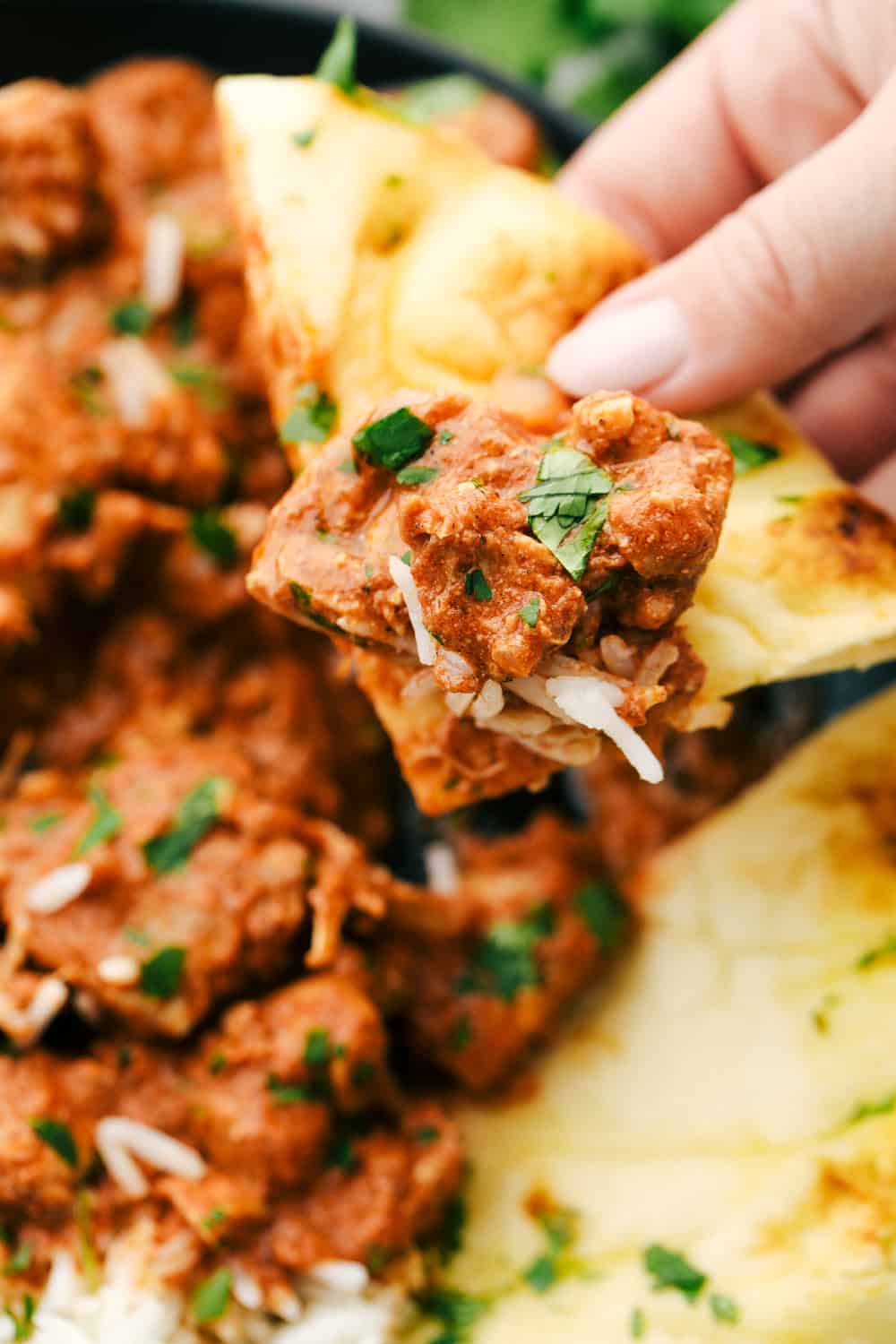 Chicken Tikka Masala up close dipped in Naan bread. 