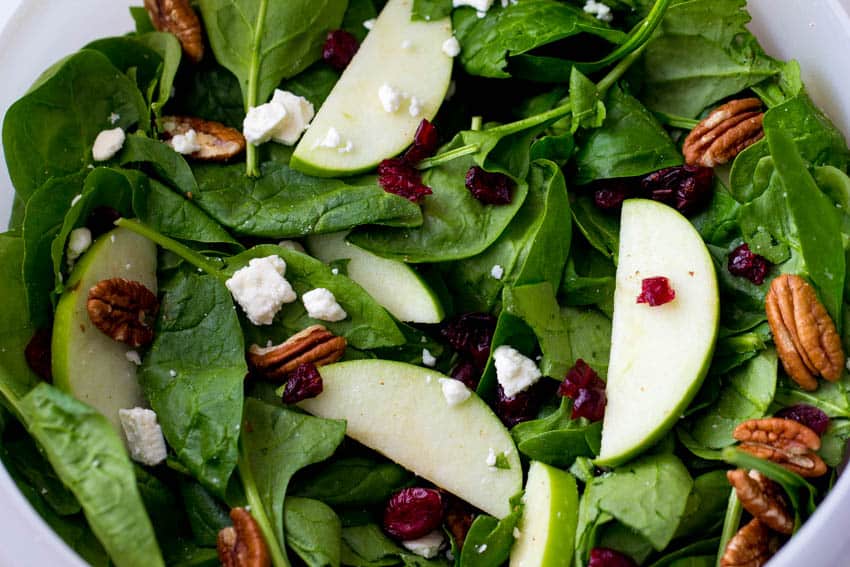 Cranberry apple pecan salad in a white bowl.