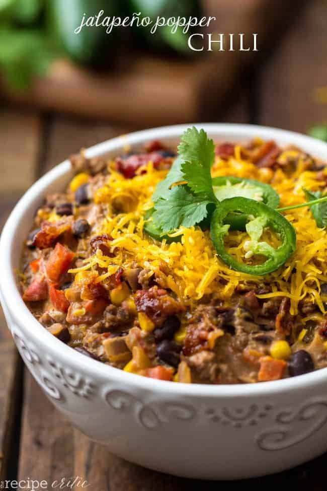 Jalapeno popper chili in a white bowl garnished with jalapeños and cilantro. 