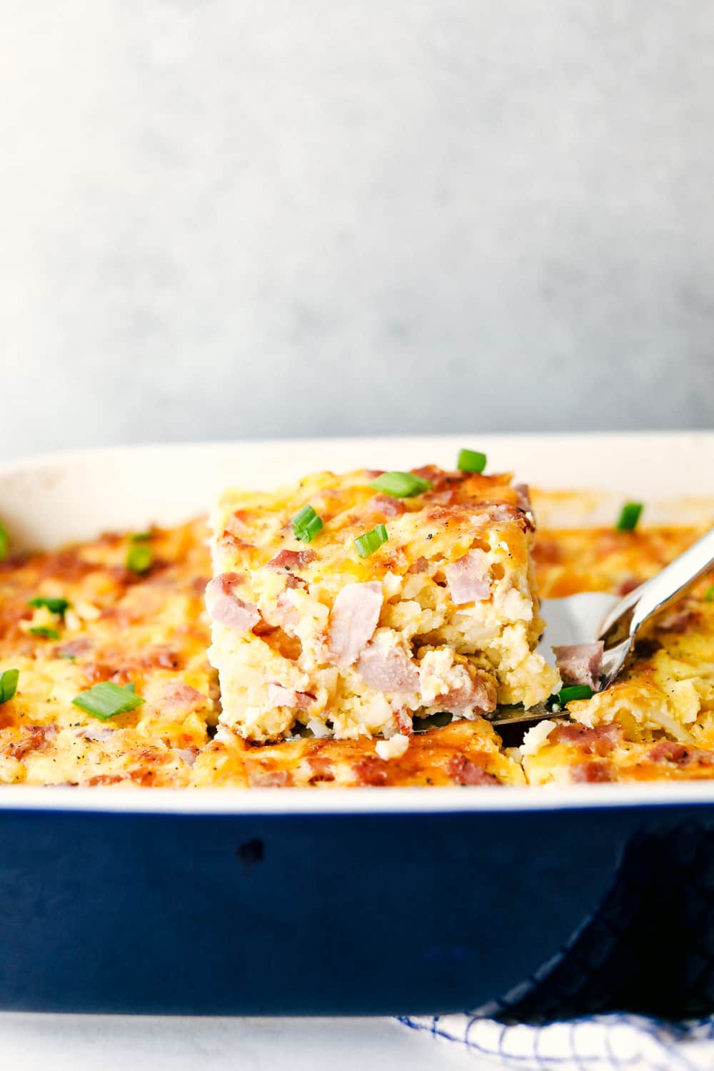 Side shot of someone lifting out a slice of casserole. 