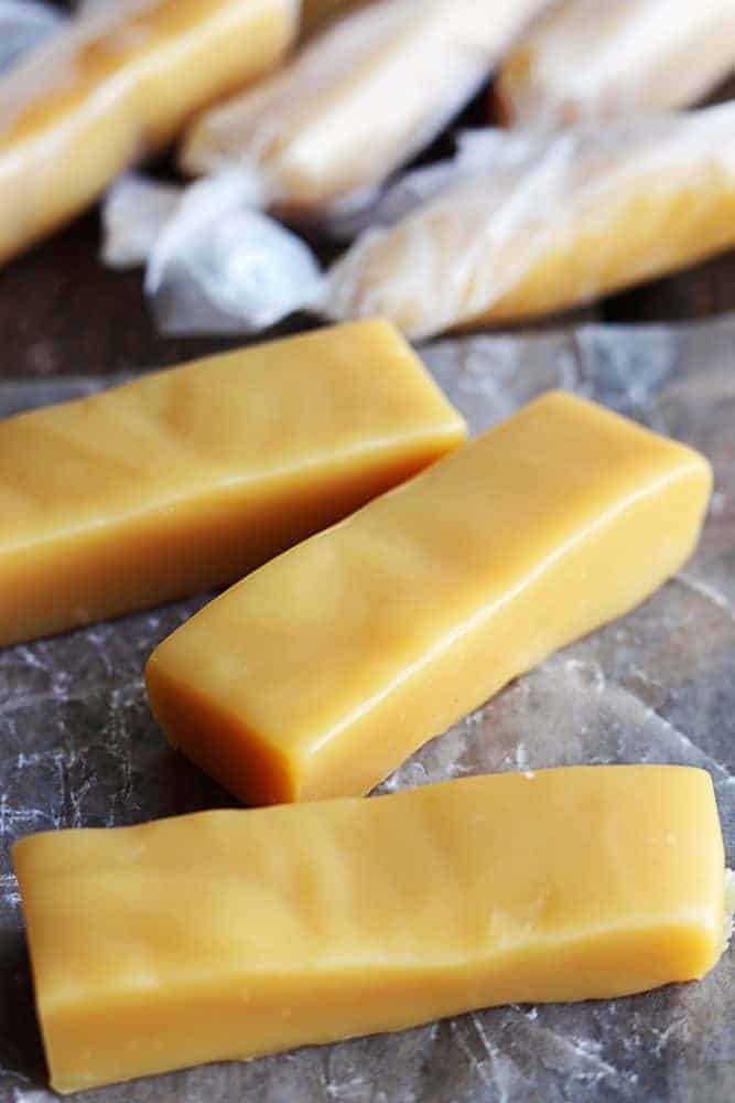 Unwrapped Microwave Caramels pieces with wrapped microwave caramels behind them. 