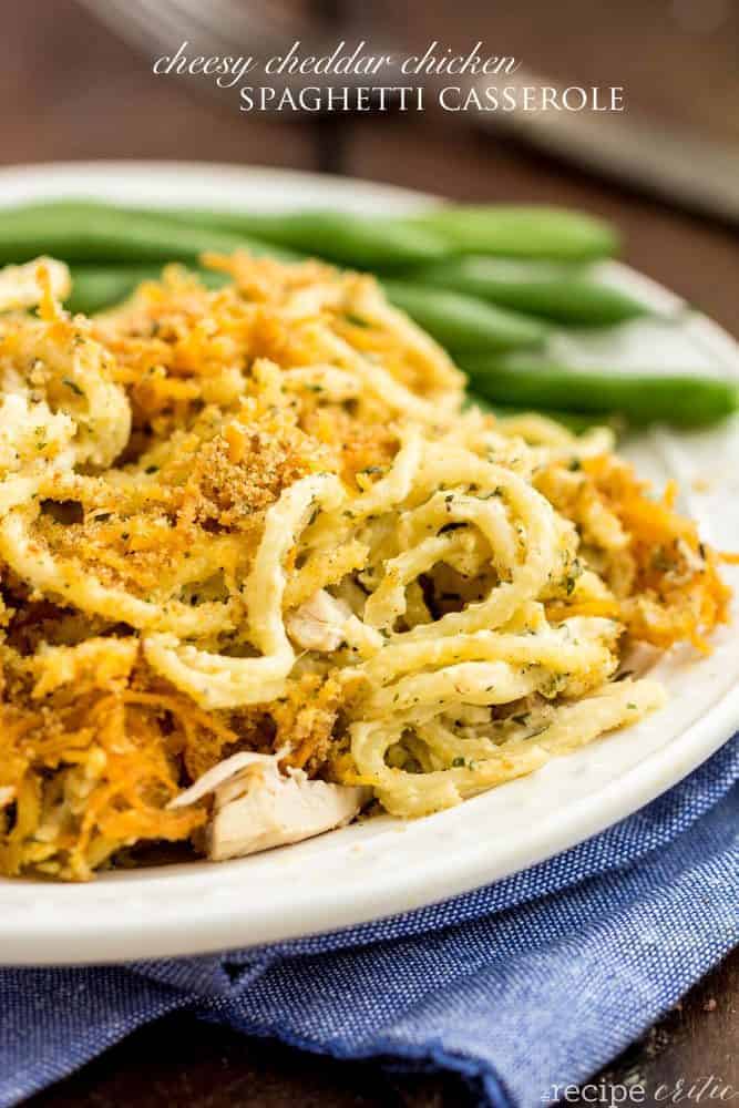 Cheesy Cheddar Chicken Spaghetti Casserole on a white plate with green beens on the side. 