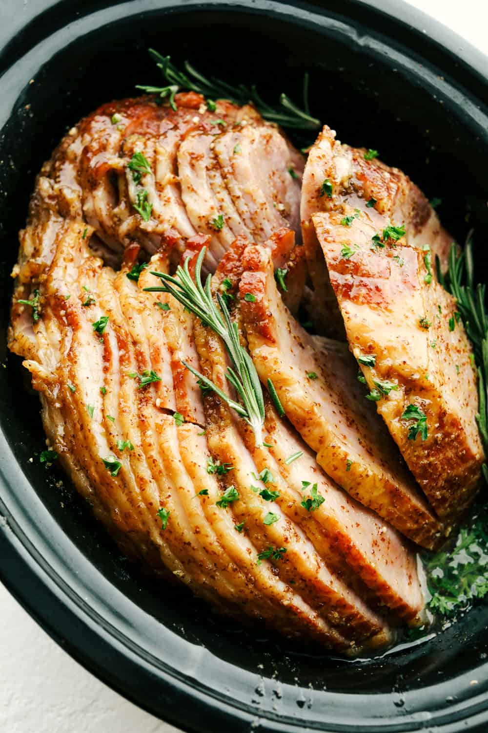 Garnished Slow cooker ham with a honey, garlic, and mustard glaze.