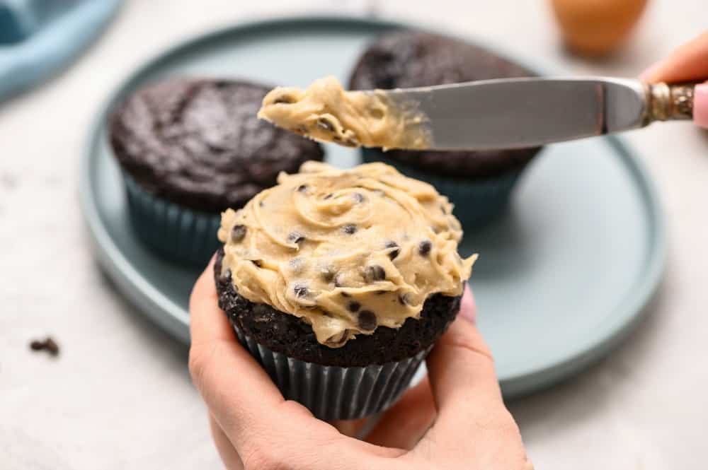 Frosting the chocolate cupcake with cookie dough frosting.