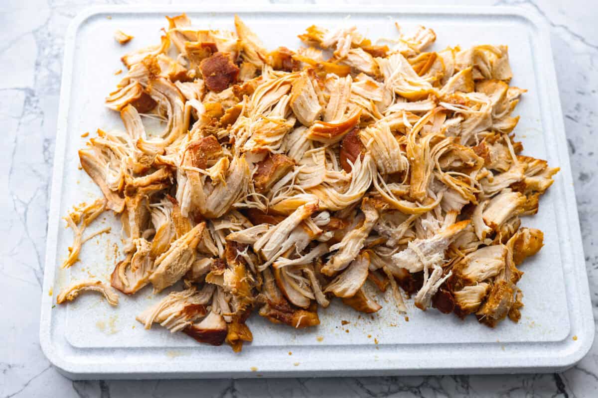 Overhead shot of chicken shredded on a cutting board. 