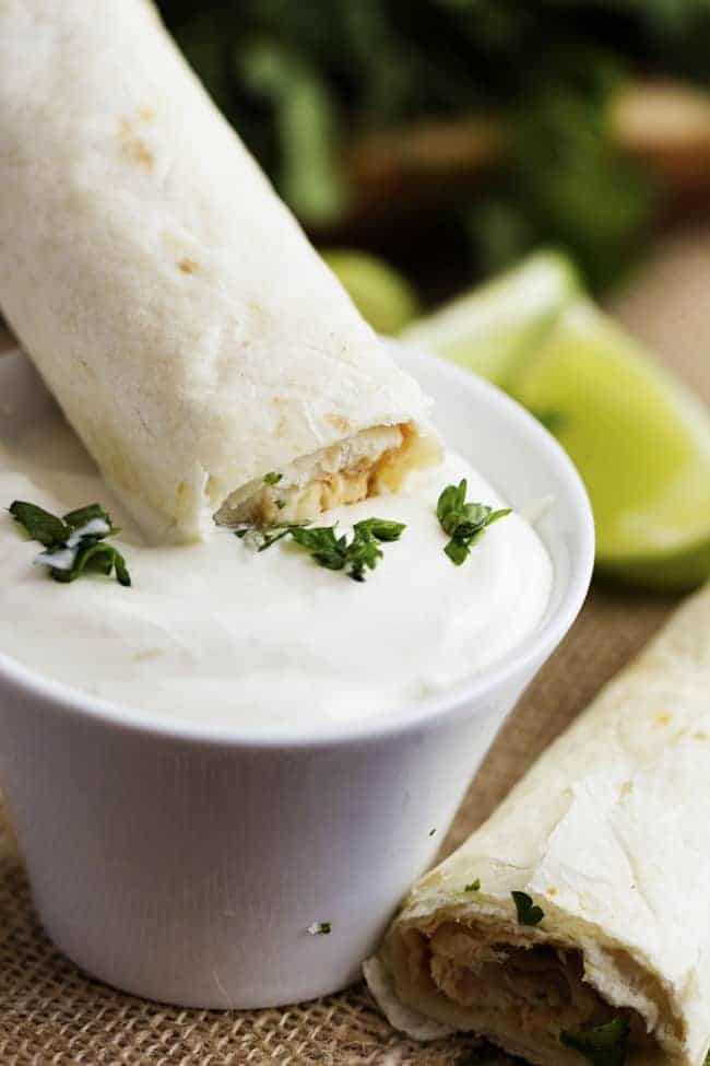 Taquito dipping into the cilantro lime sour cream dip